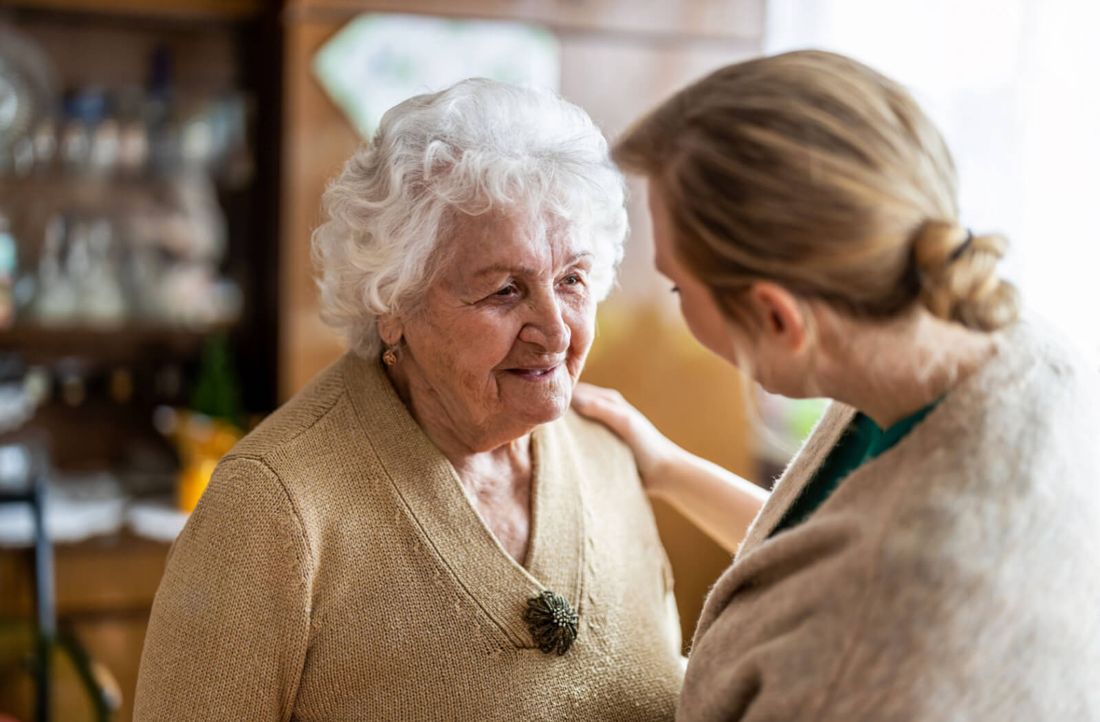 A caregiver examining an older adult woman who is experiencing disorientation and confusion.