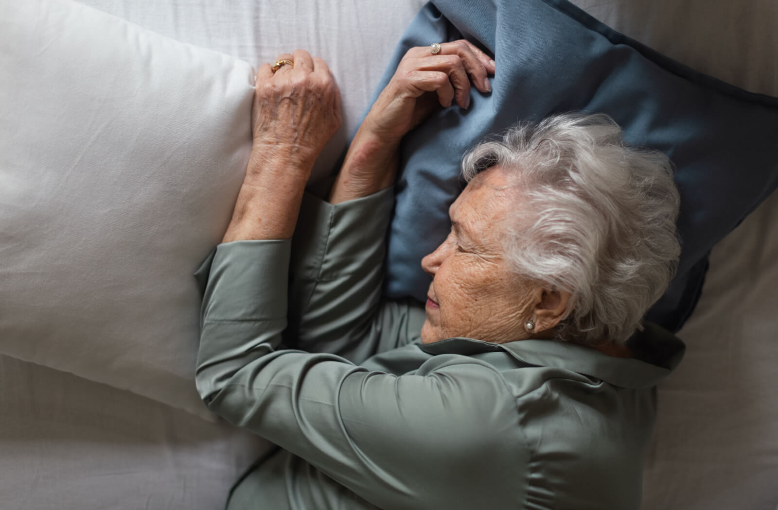 An older adult woman sleeping on her bed.