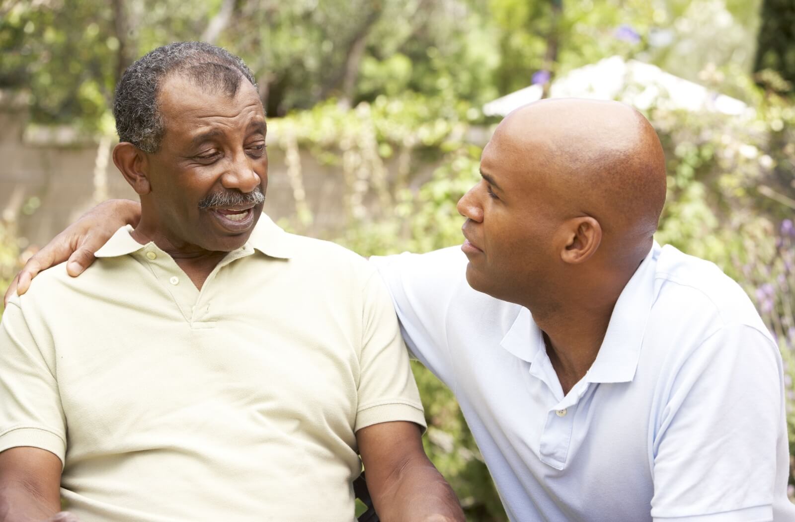 A man having a serious conversation with his older adult father outdoors.