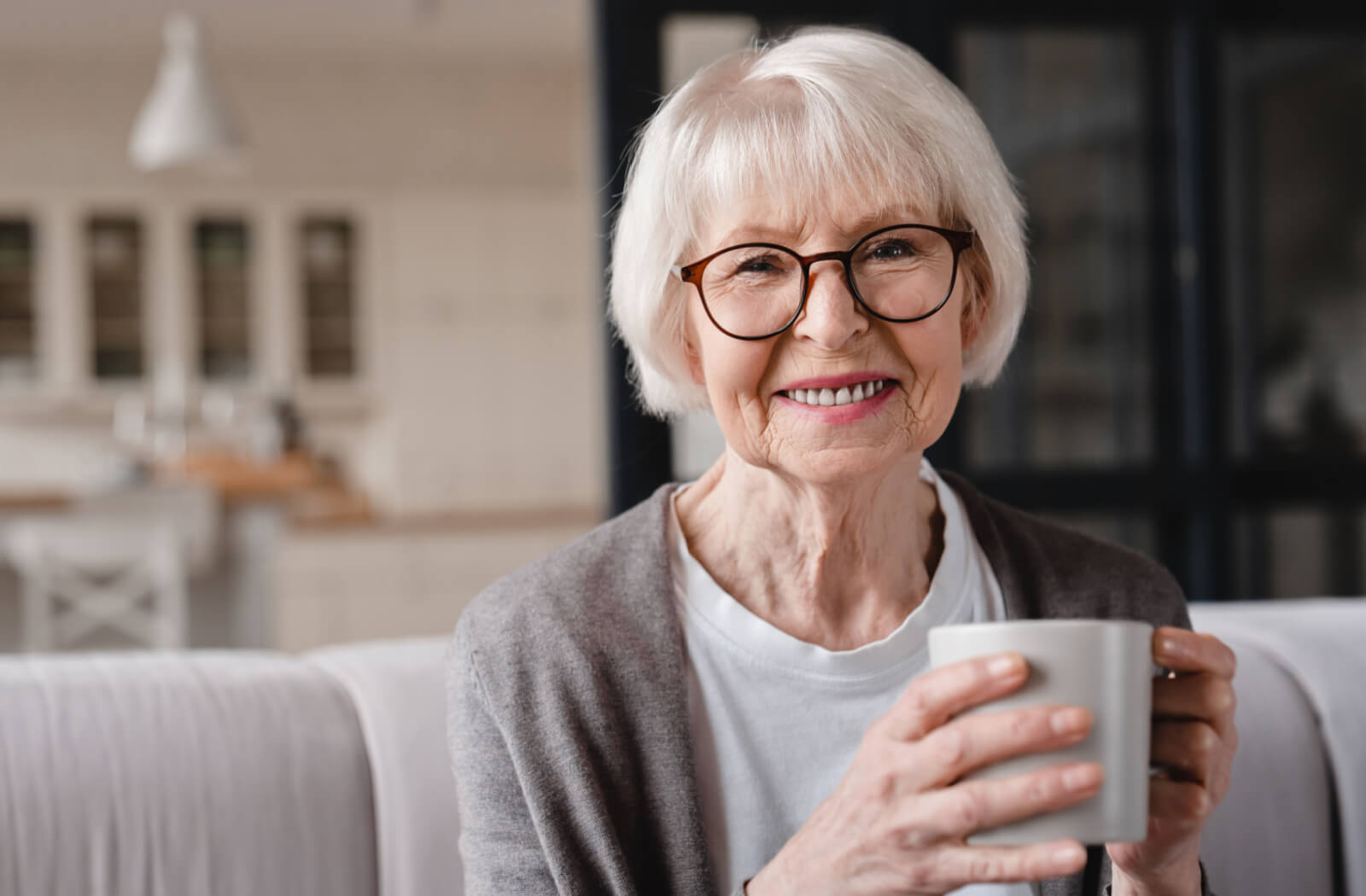 a smiling senior woman holds a cup of coffee