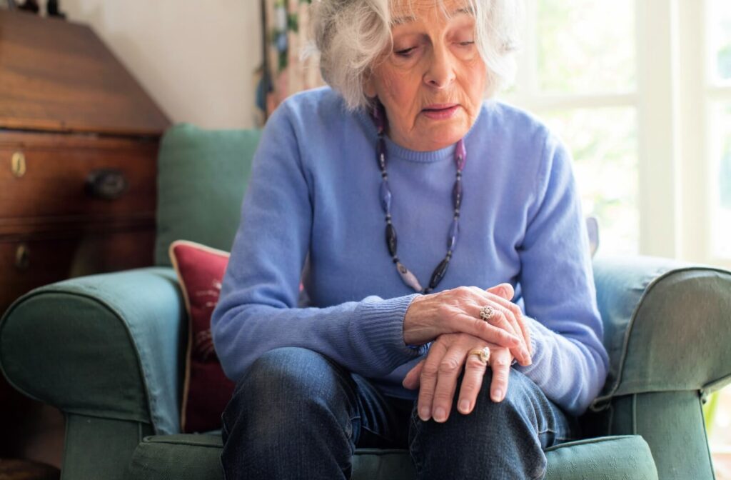 a senior woman with parkinsons sits in a chair