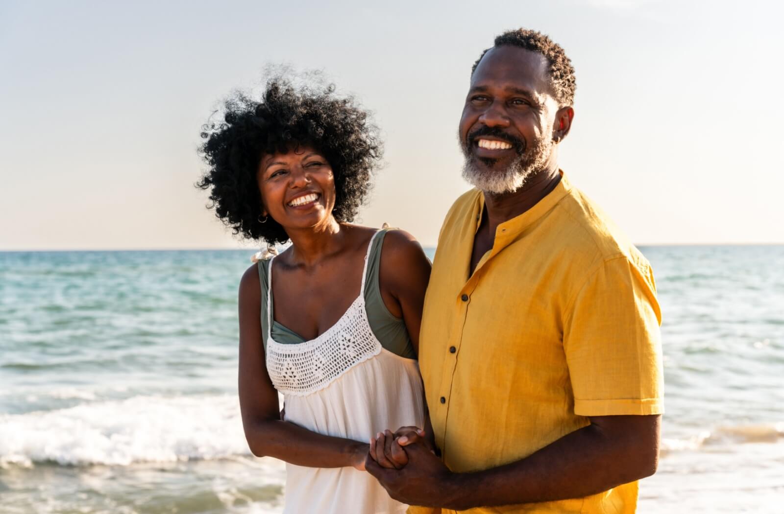 A couple of happy seniors on a date, enjoying a walk along the beach together.