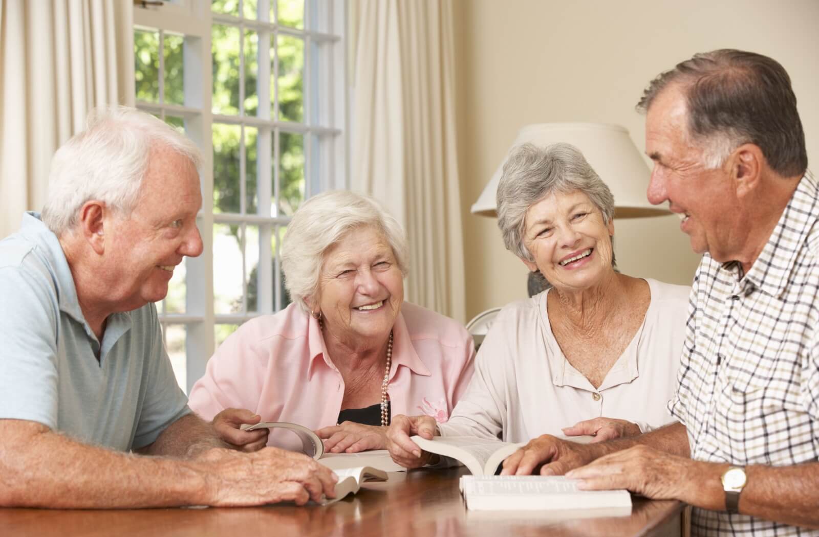 A group of seniors with books laugh as they discuss their thoughts.